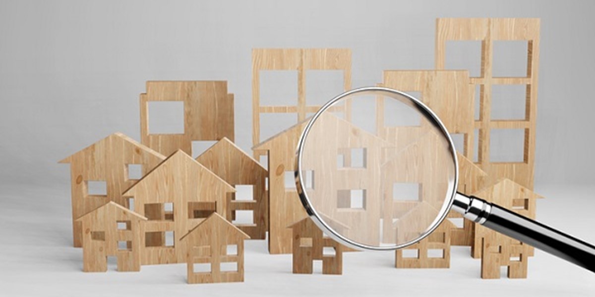 Magnifying glass over wooden shapes of buildings