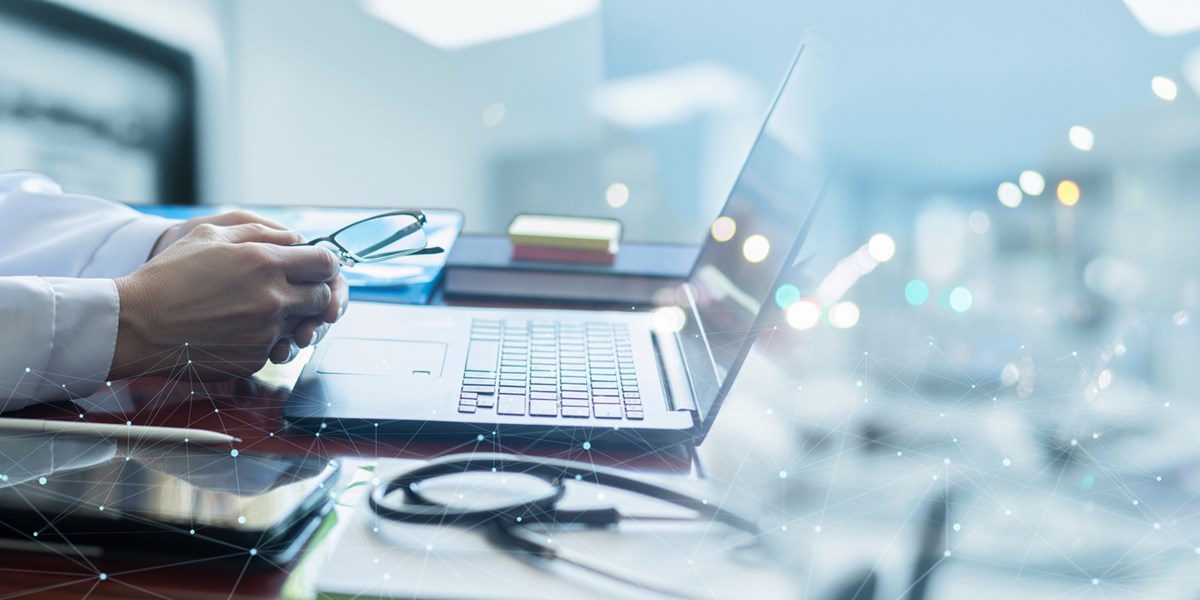Digital icons emerging from laptop in front of doctor