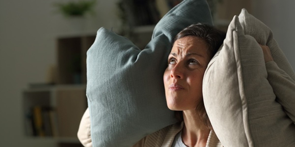 Woman pressing pillows to her ears